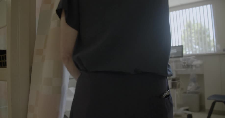 A doctor pulls aside a curtain and enters a patients room