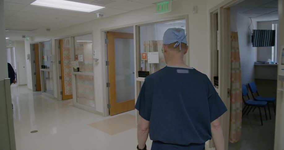 A man with blue scrubs walking in a hospital
