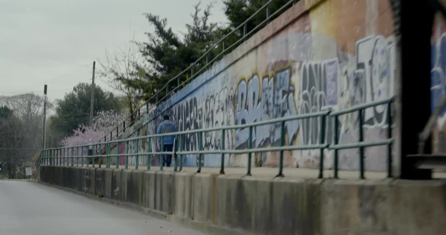 Man walks near bridge along graffiti covered wall
