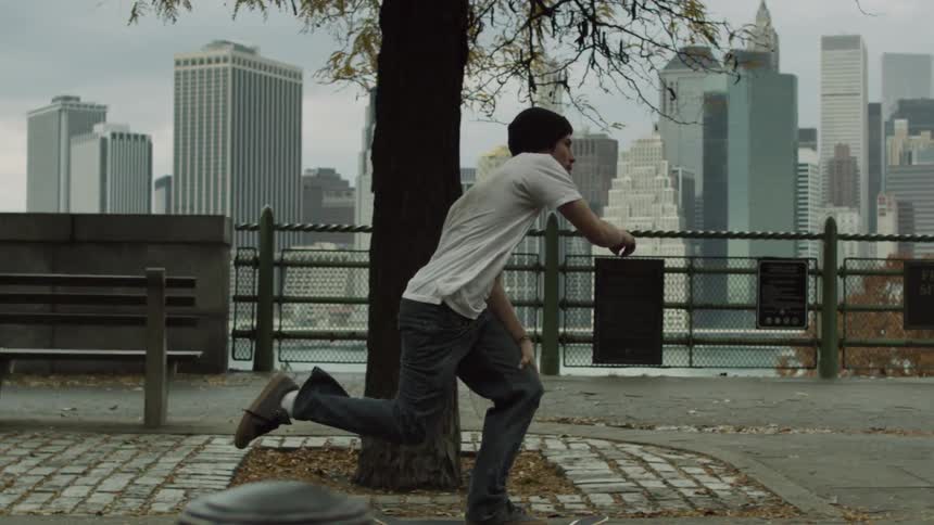 A man in a dirty white shirt skateboards on a brick path