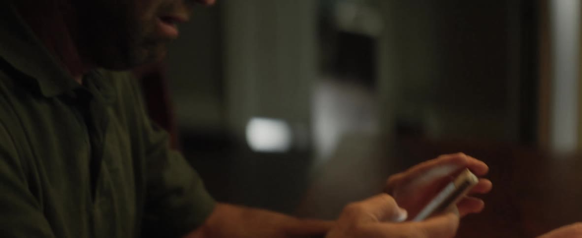 A man laughs and cries while looking at something on his phone