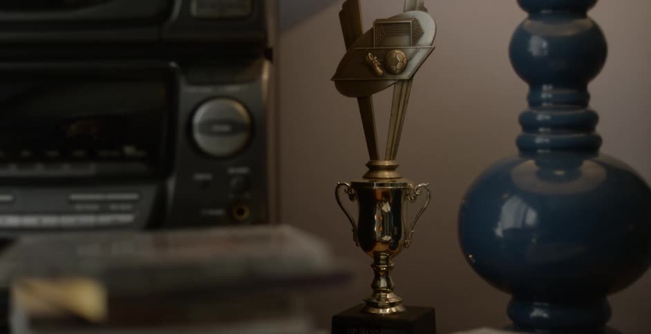 A cassette player and radio sit on a table next to cds and a trophy