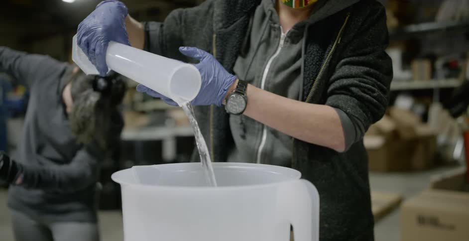 People work in a factory pouring vials into pitchers