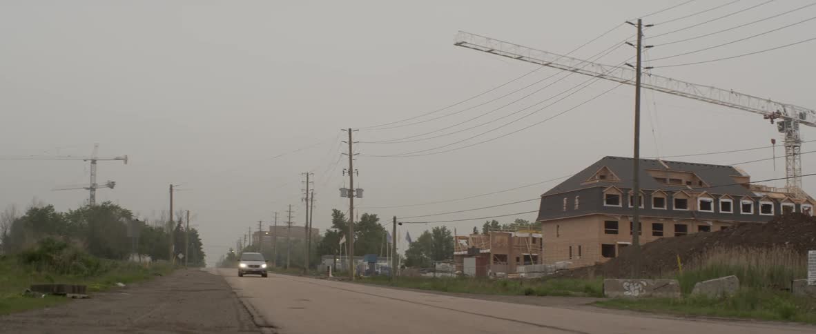 Car drives past building construction site on foggy day