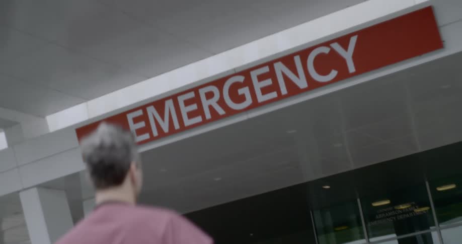 A person walks toward the entrance of an emergency room