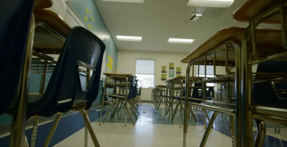 Numerous school desks are lined up in classroom without any students in it