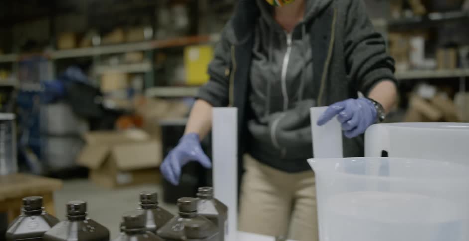 Two people wearing face masks are working with graduated cylinders as they measure out various chemicals