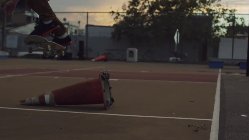 A man does a jump over a traffic on a skateboard as the sun sets