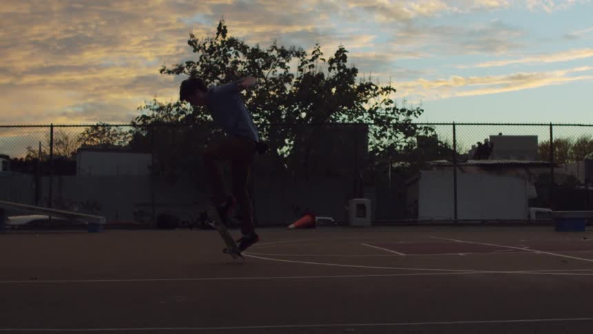 A skateboarder doing tricks on an outdoor basketball court
