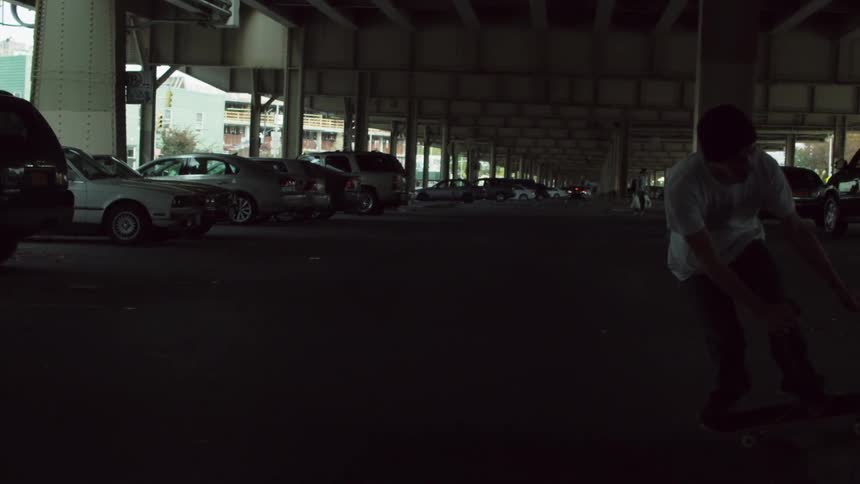 A young man attempting to perform a skateboard trick in a parking garage before he falls