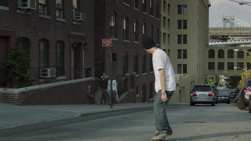 Skateboarder does a trick while going down a city street