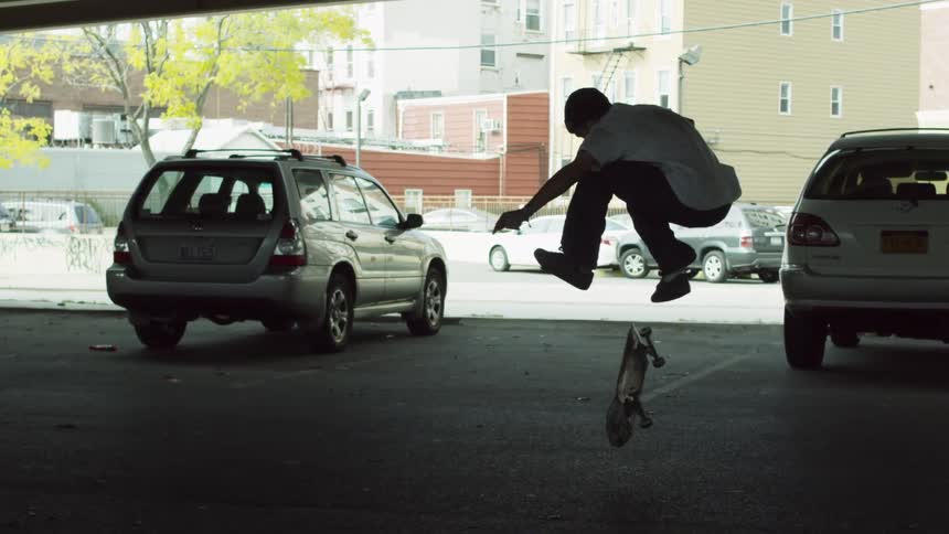 A man in a white shirt rides his skateboard