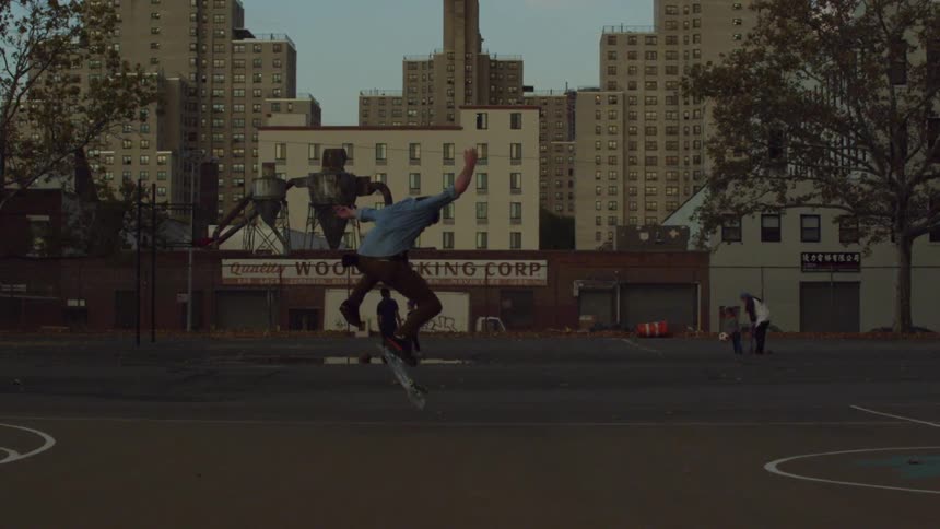 A man in a blue shirt flips his skateboard