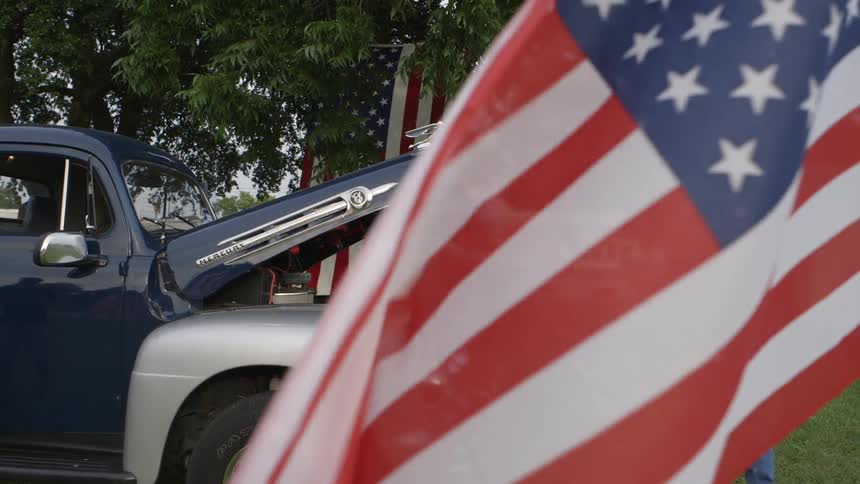 American flags fly near a vintage pickup truck