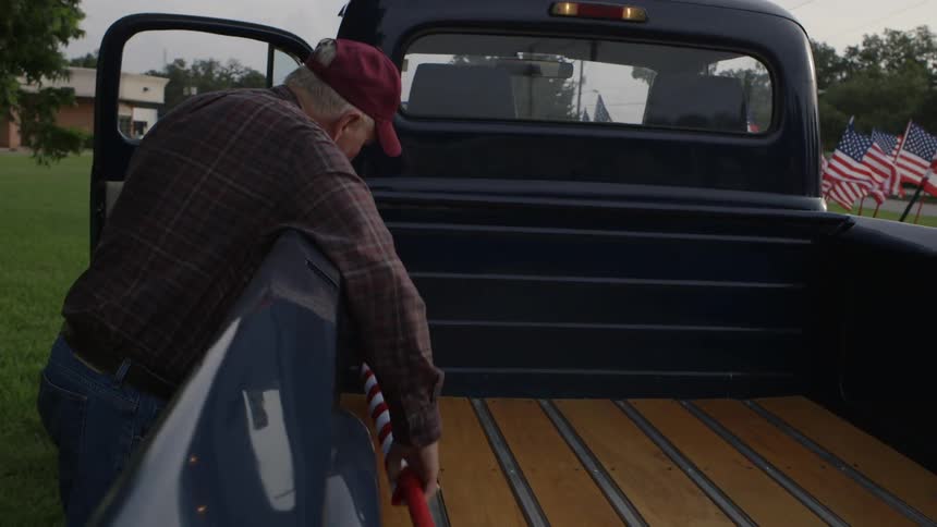 A man puts a rolled up flag in his truck