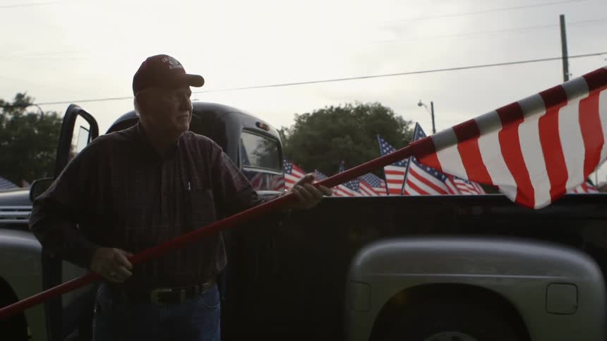 A man rolls up a flag and puts it in his truck