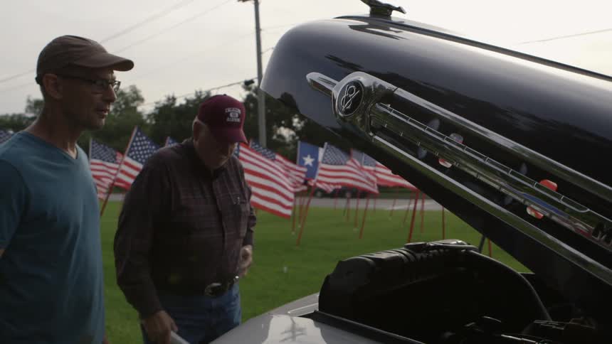 An older man opens vehicle hood to look at engine