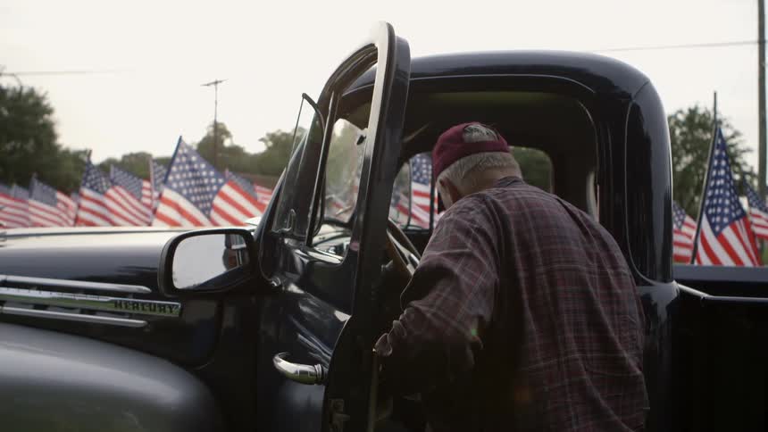 An old man climbs into a truck