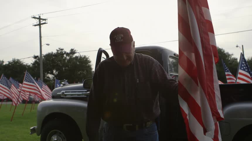 An older man laughs while holding a flag