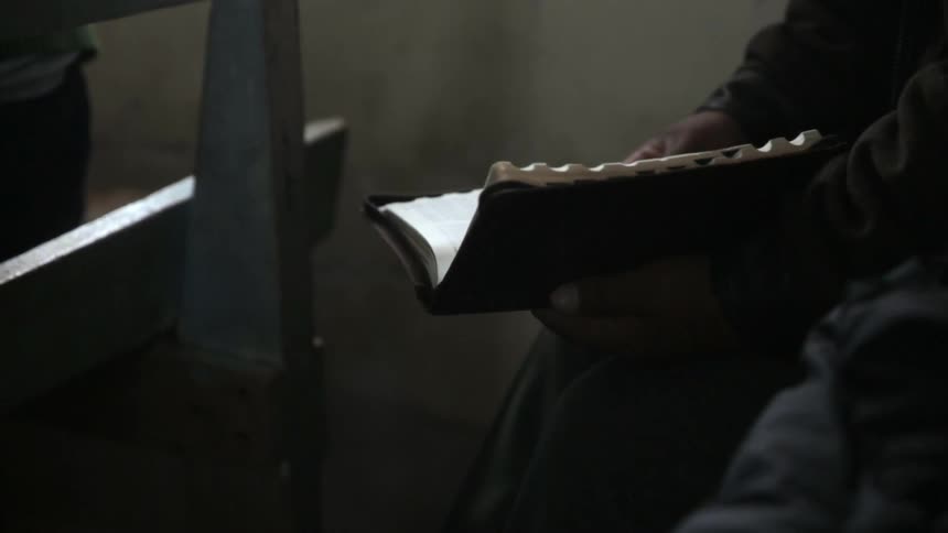 A person reads a book while sitting down in a building