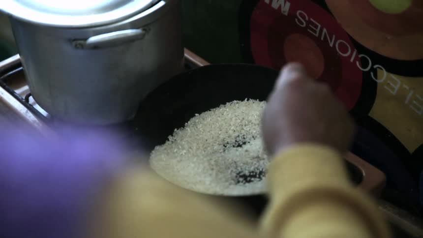 A person stirs a pan of dry grains
