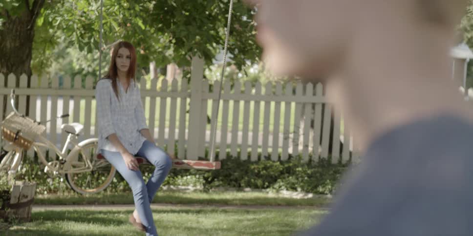 A young woman sits on a swing and swings