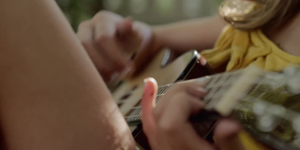 Close up of young girl playing a ukulele outdoors