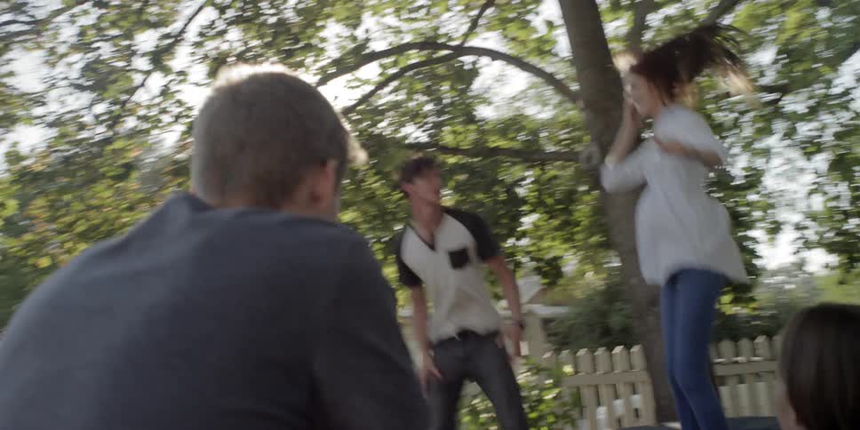Two teenagers jump on a trampoline as two others watch them
