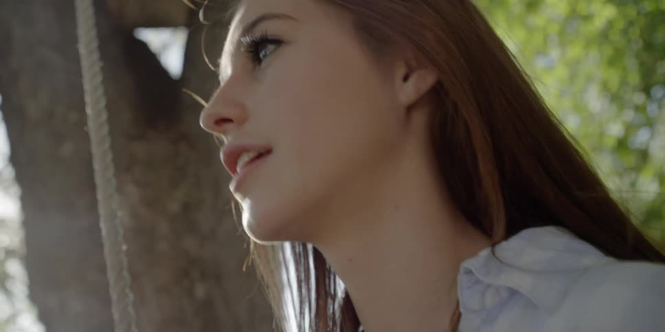Girl sits on a swing under the tree
