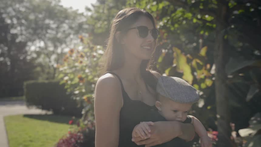 A woman is carrying her baby on the sidewalk