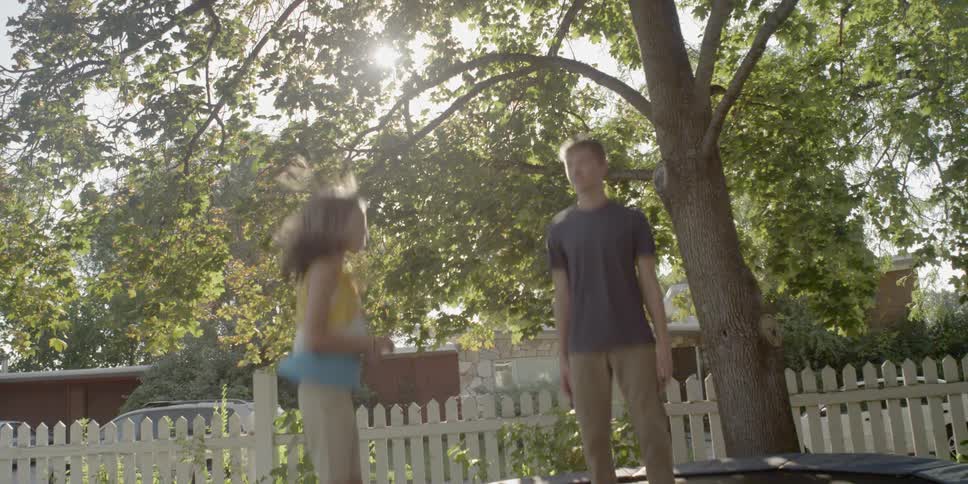 A girl and boy jump on a trampoline