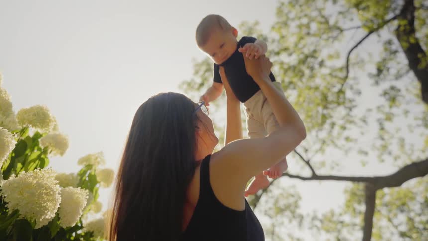 A woman raises her child in the air