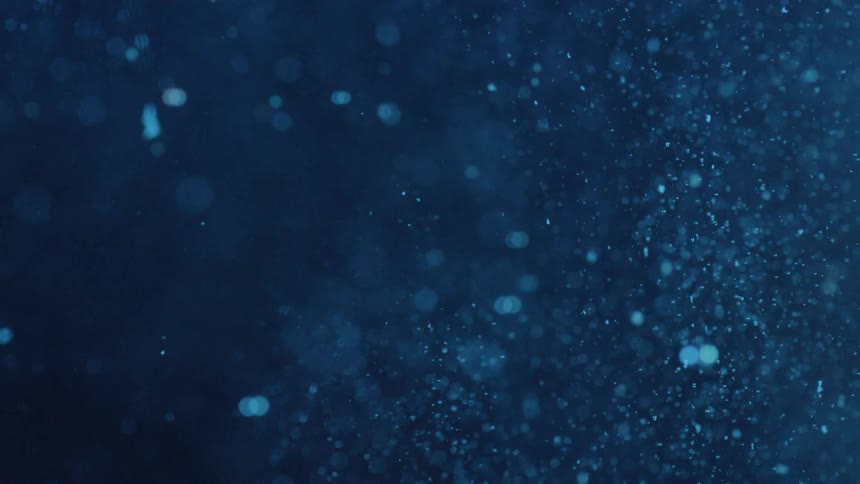 Blue liquid with white particles falling to the bottom of the glass