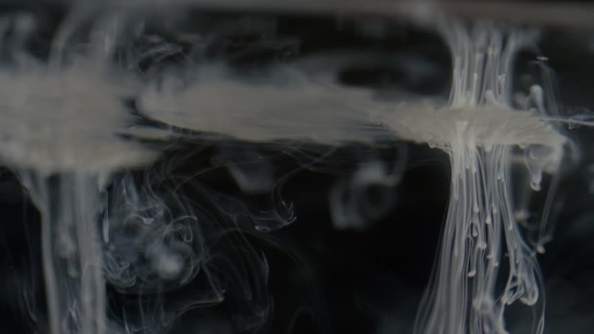 Tendrils of white spread through a clear liquid