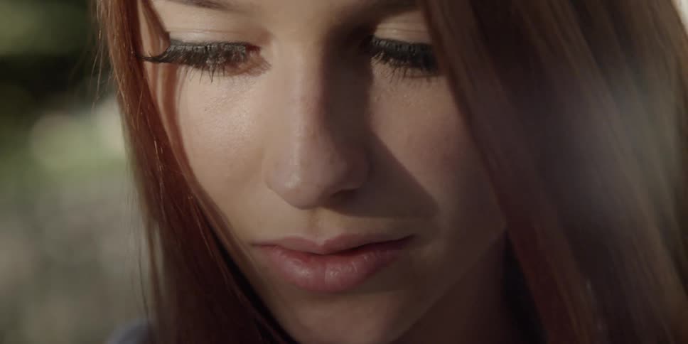 Young woman smiles faintly and looks up