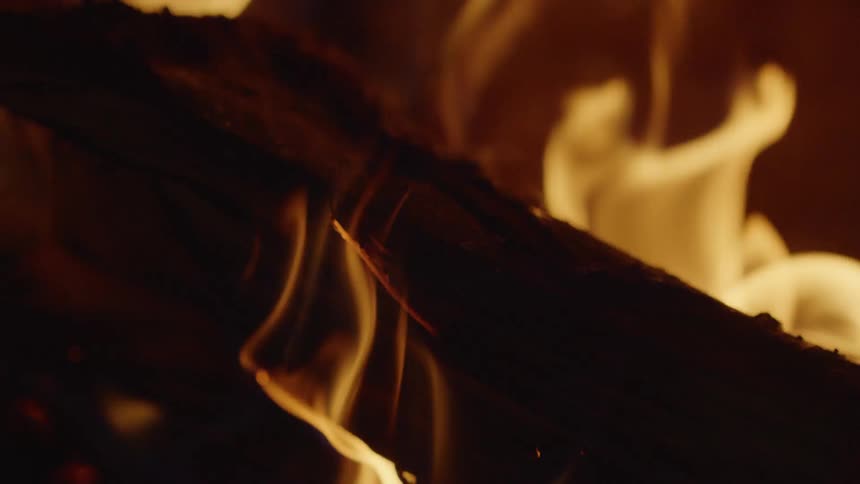 Close up of flames burning on a log at night