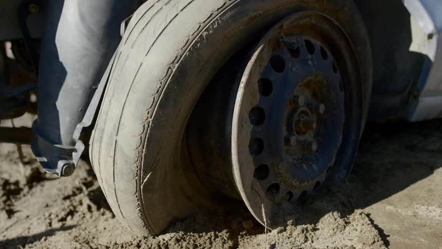 The tire on the vehicle is flat and stuck in mud