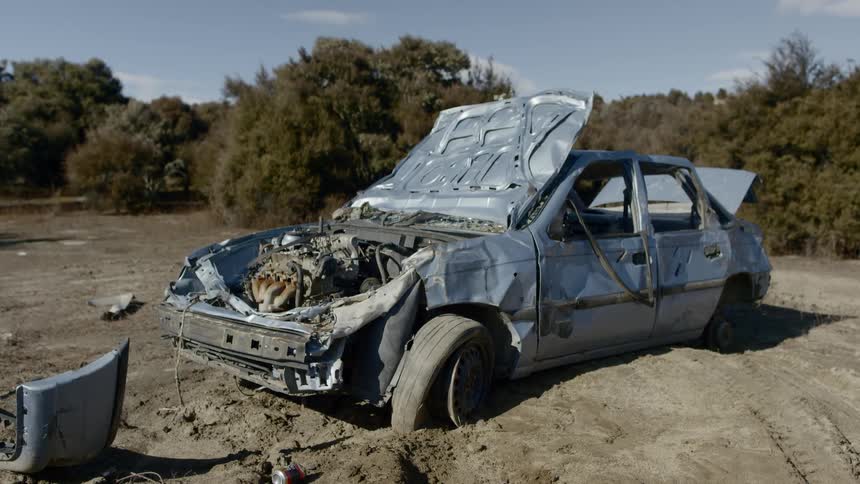 A demolished car sits in dirt