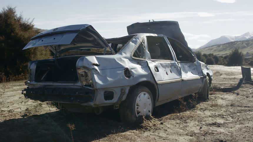 A wrecked car abandoned in a field