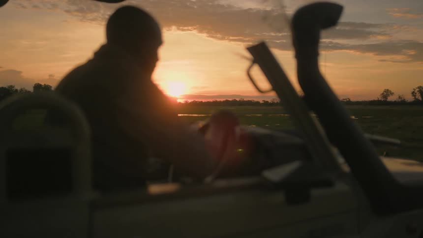 A man is driving a truck on the field near the swamp