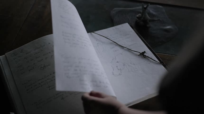 A woman flips through a notebook filled with handwritten notes and diagrams