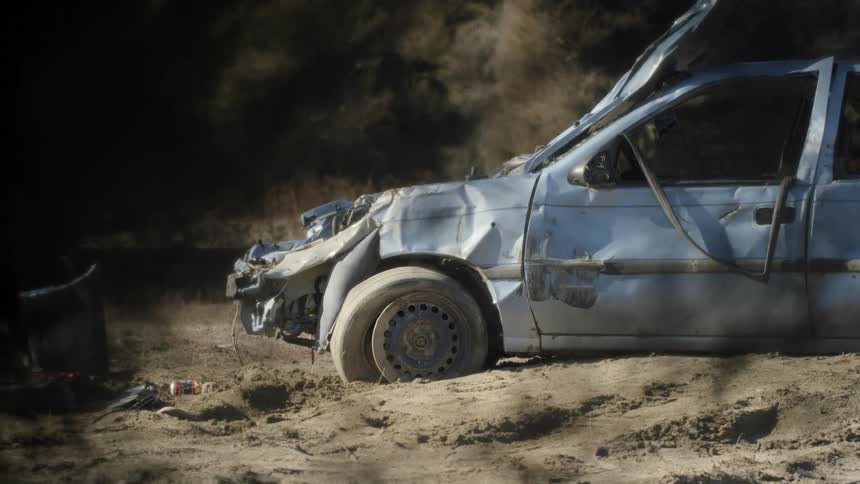 Totaled car parked on a dirt lot