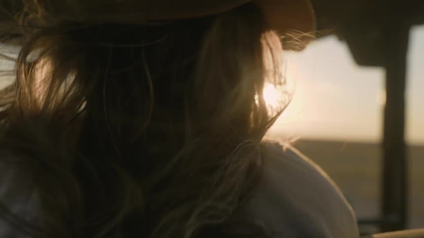 A woman is riding in a vehicle over the field