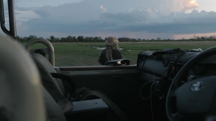 A woman walks away from a vehicle and across a field