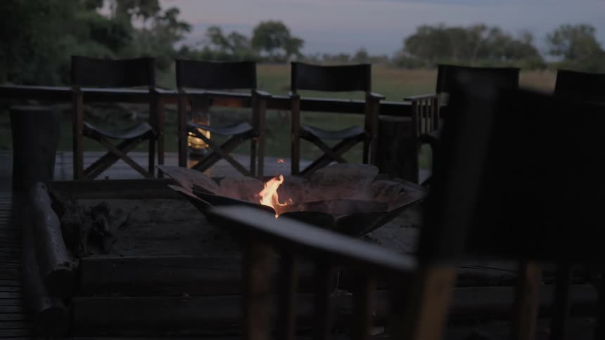 A fire burns in a fire pit on a wooden deck