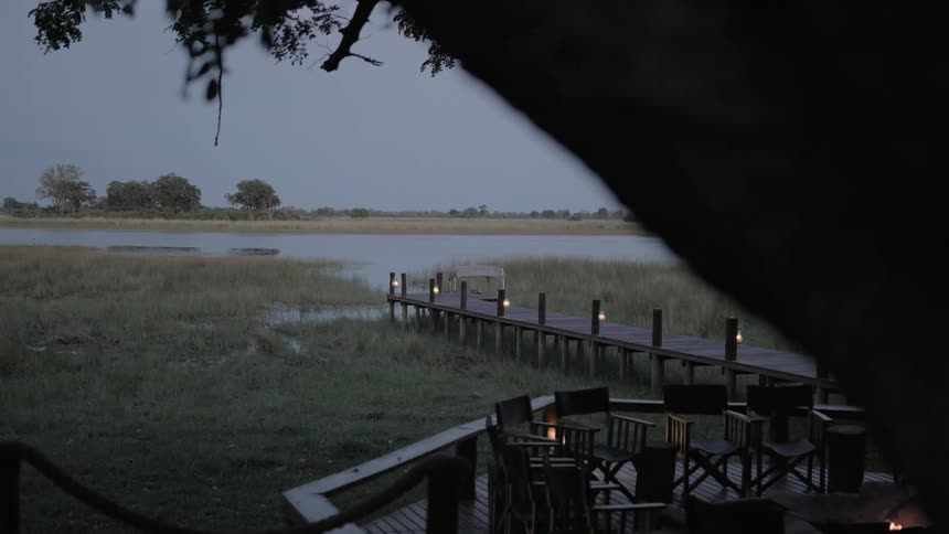 An outside deck connects to a pier that leads to a lake