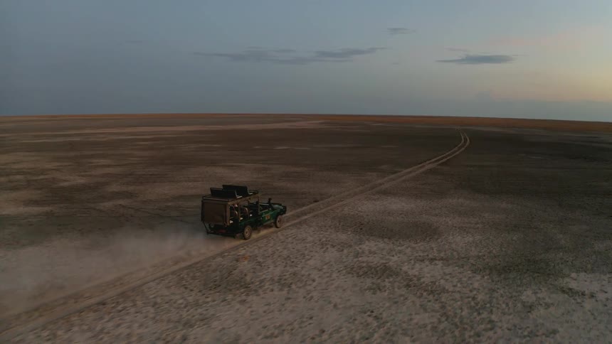 Vehicle travels down a dirt road in a field