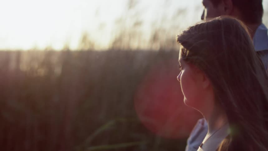 Two people walking alongside tall grass at dusk