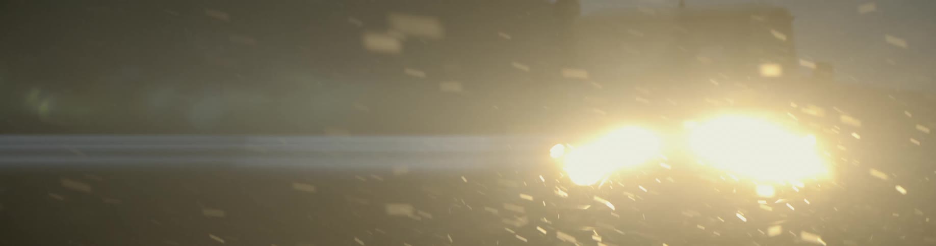 An suvs headlights shine on the falling snow at night