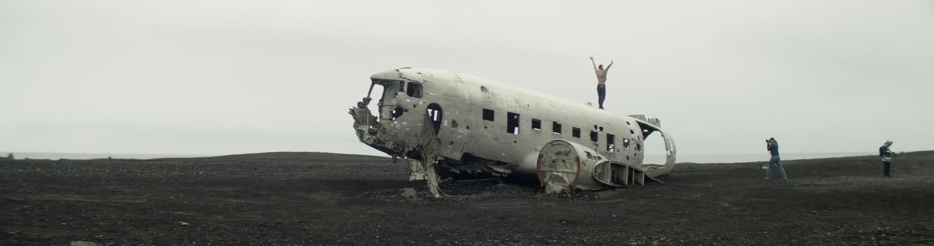 Woman poses on old airplane wreck as photographer takes pictures